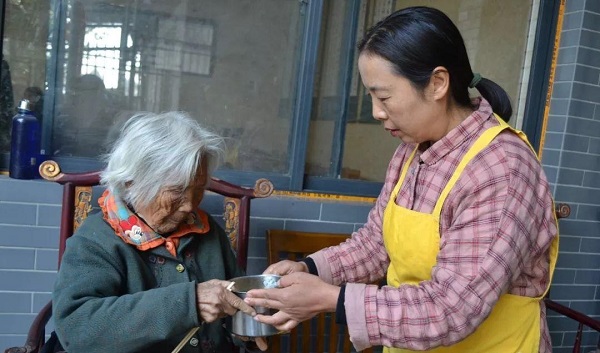 杨应芬(右)为老人端饭jpg